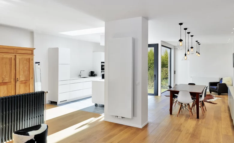 White radiator in a brightly lit room with wooden flooring, being powerflushed by a professional heating engineer